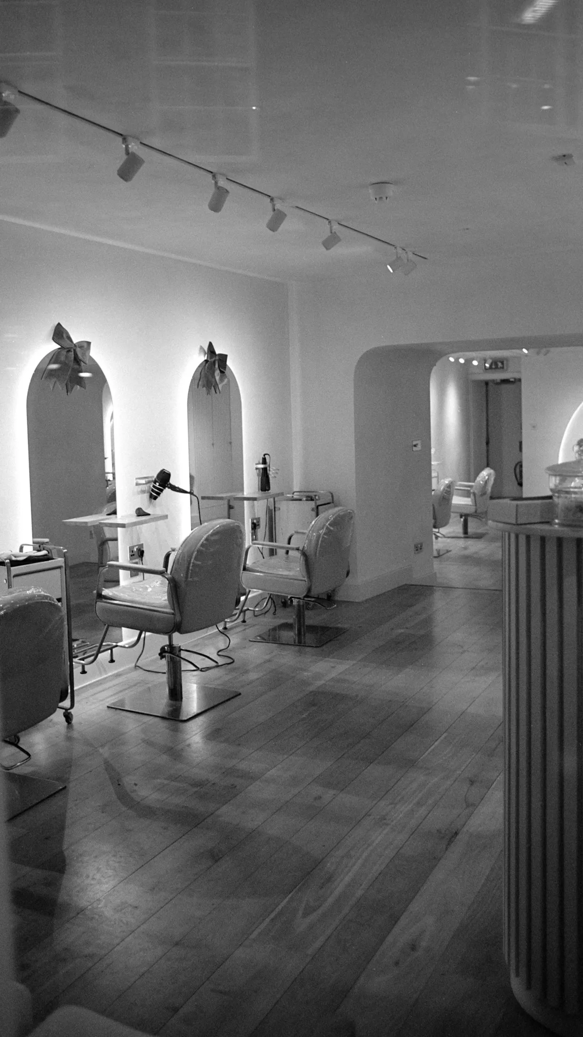 Không gian salon với gương vòm, ghế cắt tóc và tông màu trung tính